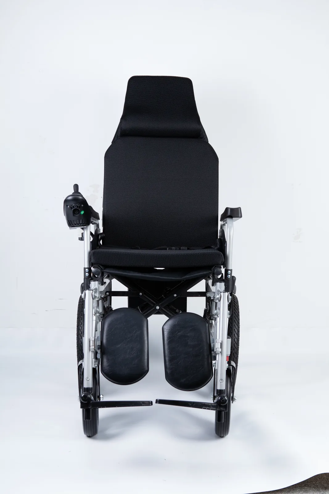 Front view of a high-back electric wheelchair featuring black mesh upholstery, adjustable footrests, and a joystick controller on the left armrest.