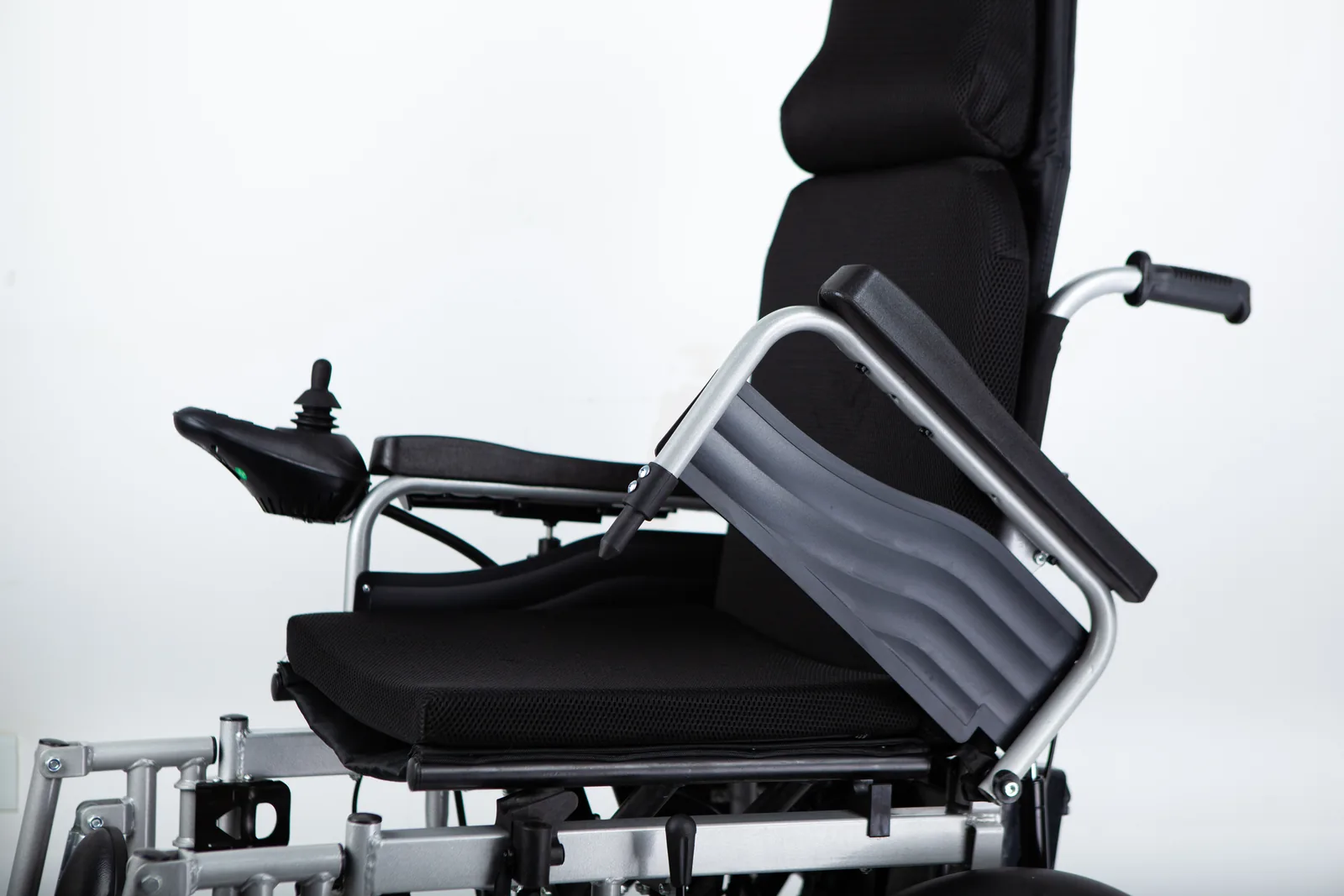 Electric wheelchair with the near armrest lifted beside a black seat, backrest and joystick control.